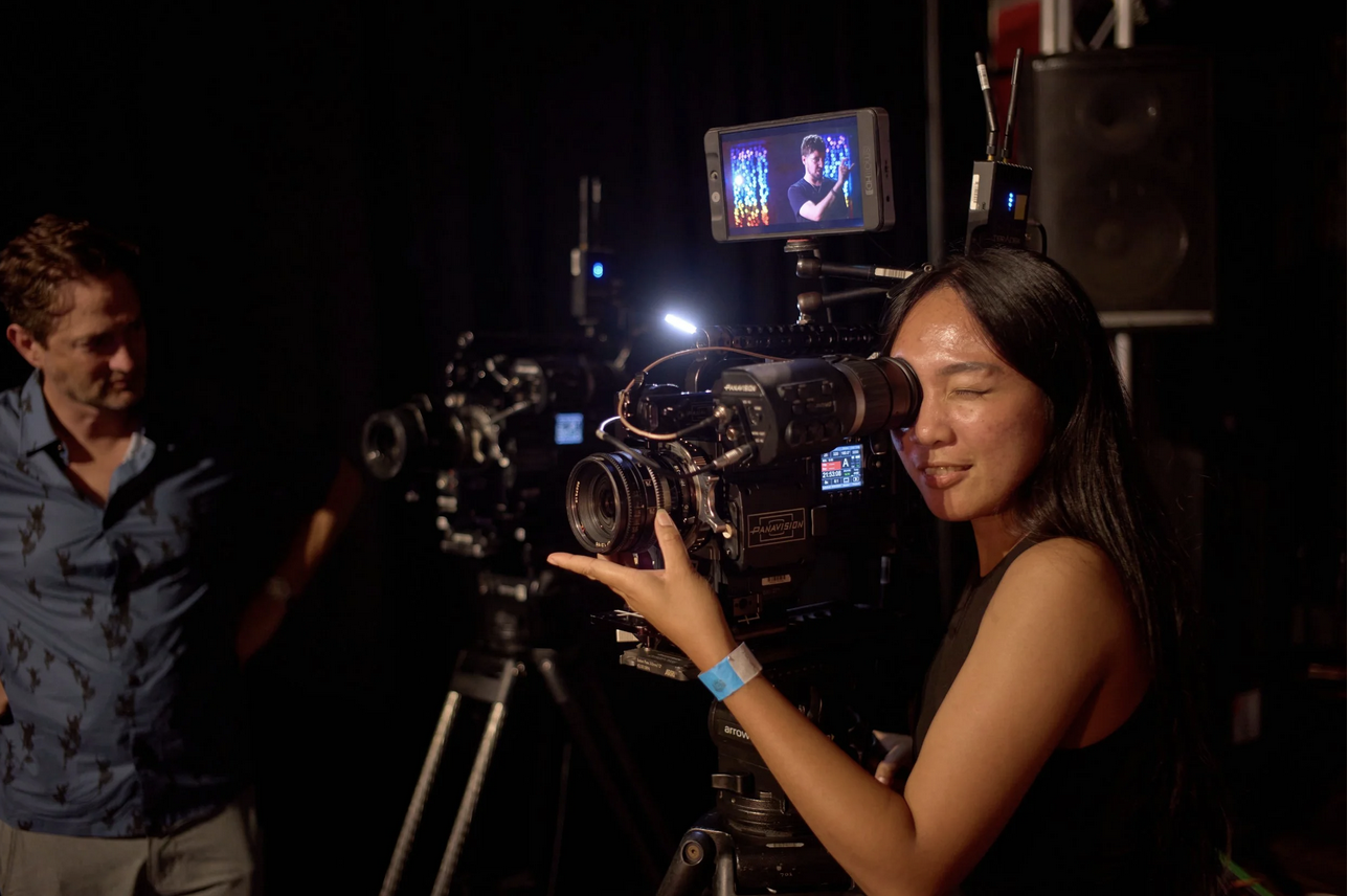 Woman looking through a camera on tripod